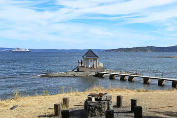 Lonely standing small cottage house in sea and footbridge connecting with coast in Oslofjord,  Norway. View to Oslo fjord in Fornebu district in Oslo, Norway.