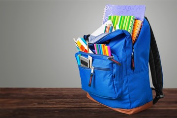 Open blue school backpack on wooden desk