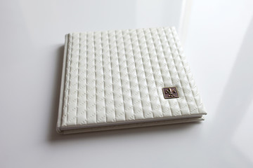 Photo book with a cover of genuine leather in the box. White color with decorative stamping .Soft focus.