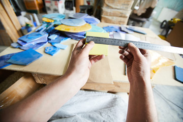 Master of mosaic measuring square pattern with ruler over workplace while choosing tiles for new order