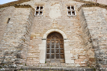 Fototapeta na wymiar Stone cross with ancient main door