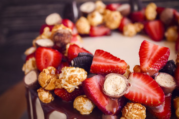 Close up of a biscuit cake with a ring of dark chocolate and fresh berries
