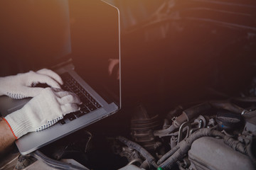 Professional car mechanic using electrnoic diagnostic equipment laptop in auto repair service.