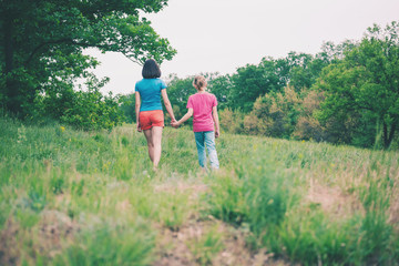 Naklejka na ściany i meble The boy walks with his mother in the meadow.