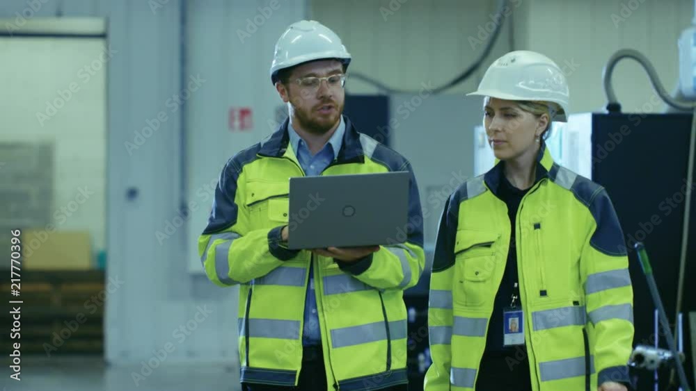 Aufkleber male industrial worker and female chief mechanical engineer in walk through manufacturing plant whil