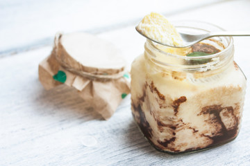 Coffee-flavored Italian custard dessert Tiramisu in a small jar with tea spoon on top of it
