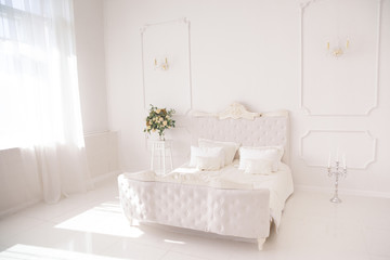 Fototapeta na wymiar bedroom in soft light colors. big comfortable double bed in elegant classic bedroom