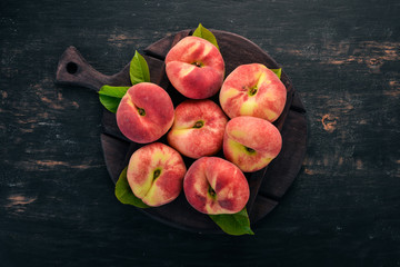Flat peach with green leaves On a black wooden background. Top view. Free space for your text.