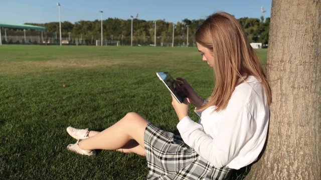 Young woman with a tablet in the park.