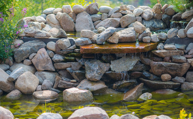Fototapeta na wymiar Garden waterfall coming from the rocks