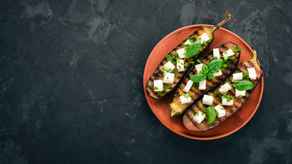 Eggplant grilled with feta cheese and basil. Healthy food. On the stone table. Top view. Free space for text.