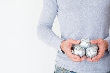 christmas balls. elegant festive decor and new year holiday ornaments concept. man holding silver glittery baubles in hands.