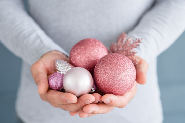 christmas balls. elegant festive decor and new year holiday ornaments concept. man holding rose gold glittery baubles in hands.