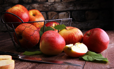 Ripe red apples with leaves on wooden background