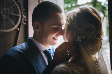 A beautiful bride and a stylish groom stand and hug in the back light. Wedding concept. Wedding portrait of cute and smiling newlyweds.