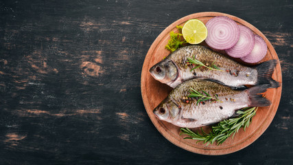 Raw Fish with Spices and Vegetables. Carp On a wooden background. Top view. Copy space.