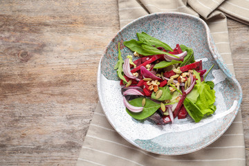 Plate with delicious beet salad on wooden background, top view