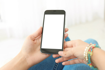 Woman holding smartphone with blank screen on light background. Mockup for design