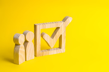 Figures of people are standing near a huge tick in the box. Voters take part in voting for a...