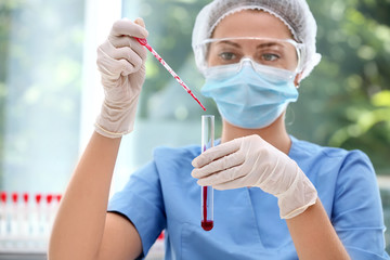 Scientist dripping blood into test tube in laboratory