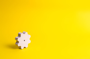 A wooden gear on a yellow background. The concept of technology and business processes. Minimalism. Mechanisms and devices. Work, moving forward. Development and development.