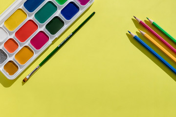 Fototapeta premium Artist home office desk. yellow Paper with watercolors paint brush isolated. Flat lay,creative minimal mock up template.School supplies. set of new watercolor paints.Copy space
