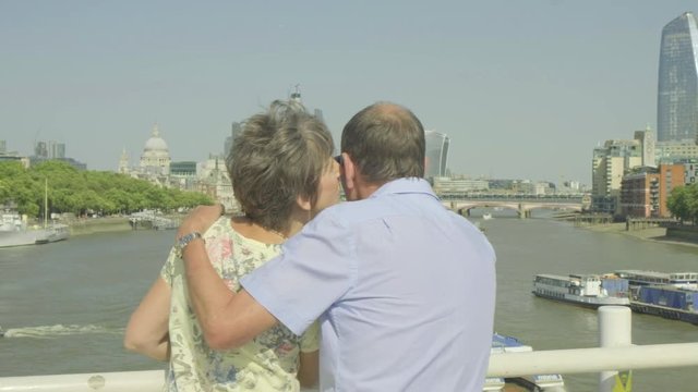 Active senior caucasian tourist couple looking at a map on waterloo bridge london with the river thames and london skyline behind while on vacation themes of sightseeing active seniors love togetherne