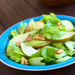 Fresh celery, pear and walnut salad on blue plate, photographed with natural light (Selective Focus, Focus in the middle of the salad)