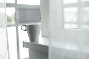 A cup of coffee on the windowsill. Big window. Scandinavian style