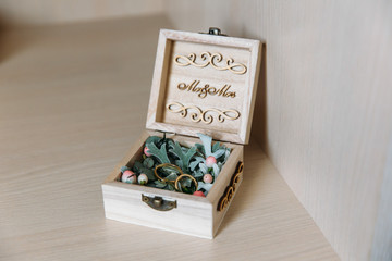 A close-up of the gold rings lie in a jewelry box adorned with hvoy branches, engraved with 