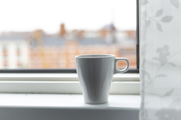 A cup of coffee on the windowsill. Big window. Scandinavian style