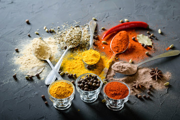 Various spices(pepper ground turmeric ginger cinnamon grass seasoning) in metal antique spoons on stone beton table. Top view