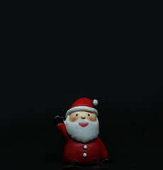 Cute santa claus doll in black background with copyspace above