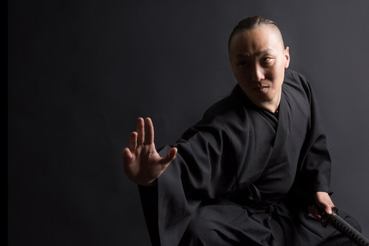 A samurai man in black kimano on a black background