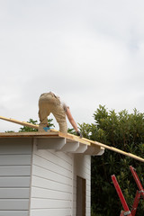 man roofer craftsman on the roof of a wood house under construction