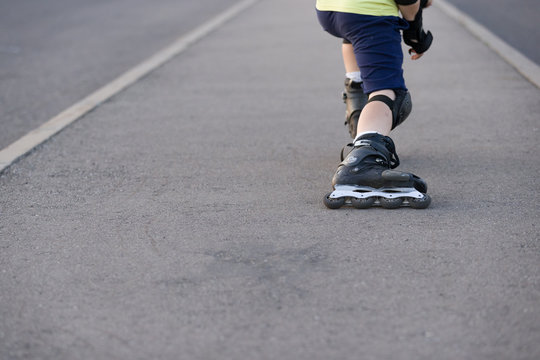 Closeup of black roller skates or rollerblading. Roller skate legs of a child in the park. Boy's legs in roller blades.