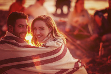 Couple enjoying with friends at sunset on the beach