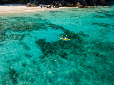 Aerial Drone View Of A Sea Kayak Exploring A Beautiful Tropical Coral Reef Next To A Remote Island