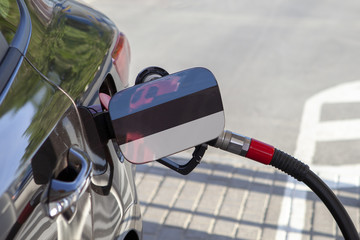 Fueling car with petrol pump at a gas station.