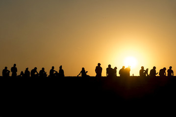 Fototapeta na wymiar Silhouette peoples sitting on fortress wall enjoying in sunset. Tourist people at Kalemegdan, Serbia. 