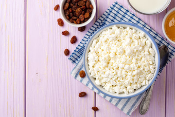 Cottage cheese in blue bowl on purple wooden background