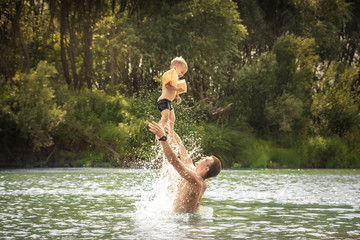 Happy father playing son kid throw up swimming lifestyle portrait concept happy paternity and childhood during summer countryside holidays.
