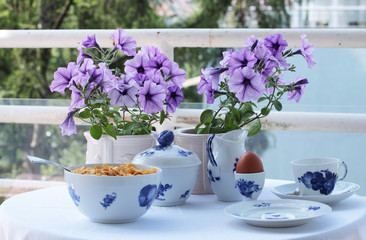 Fototapeta na wymiar Balcony Breakfast table with purple flowers and white and blue China
