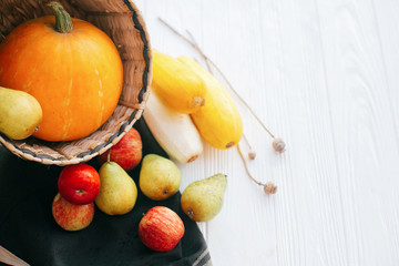 Hello autumn concept and Fall Harvest. Pumpkin and zucchini in stylish straw basket with apples and pears on white wooden background in light, Space for text. Happy Thanksgiving