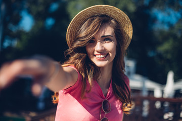 Closeup portrait of effective girl with long curly hair smiling to camera having fun on the beach, dancing and smiling, vacation mood.Nice laughing girl in hat