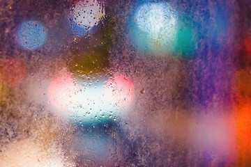 Rain drops on the window in the night city. Blurred background