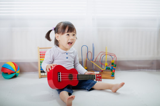 baby girl play ukulele at home