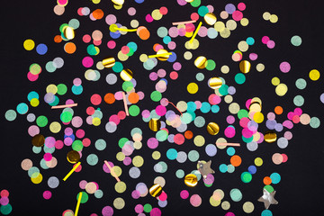 Fototapeta na wymiar Top view of colorful confetti on black background