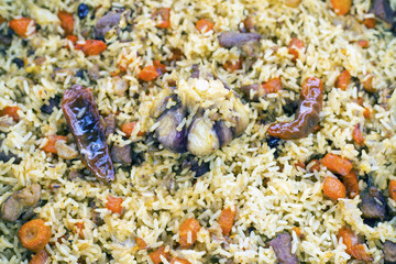 Fresh pilaf with meat, pepper, carrots and garlic, in a cast-iron cauldron. Desktop screen saver or background.