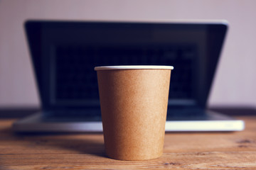 paper cup of coffee on a laptop background, working table
